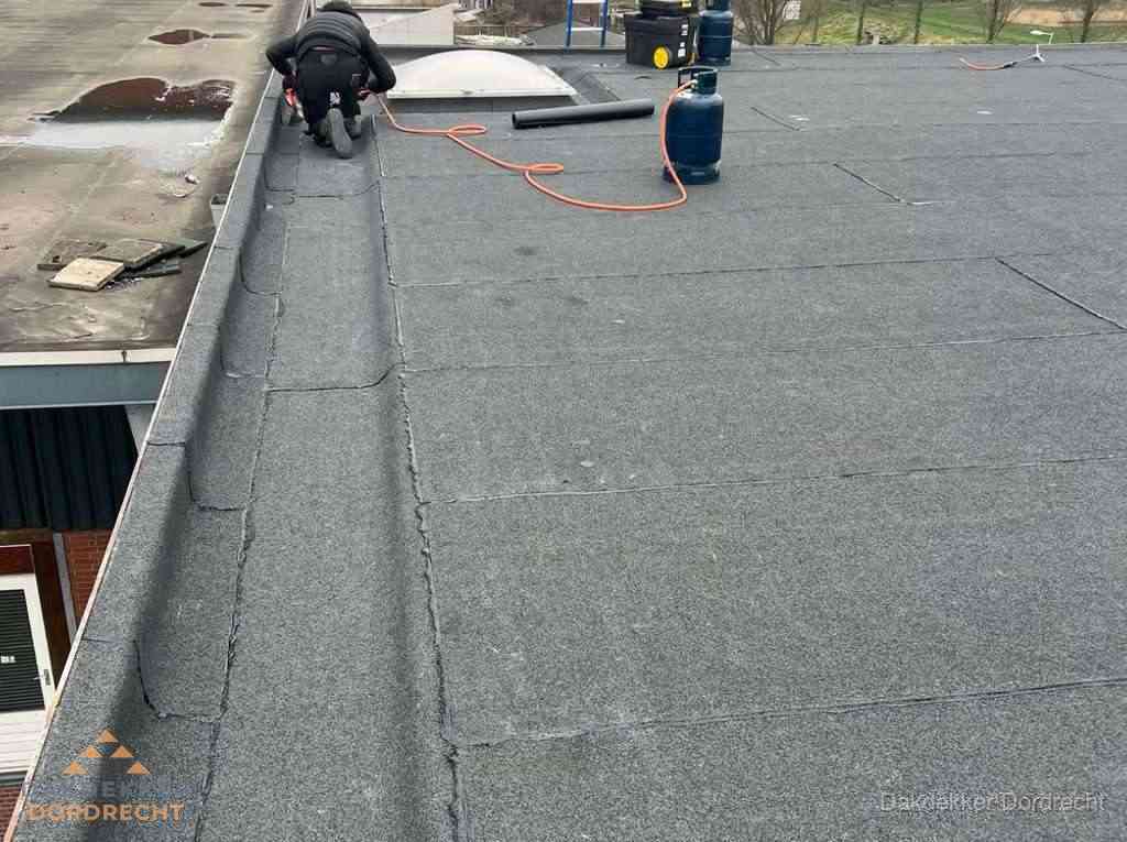 Dakdekker repareert bitumen dakbedekking op groot plat dak in Dordrecht Dakdekker repareert bitumen dakbedekking op groot plat dak in Dordrecht